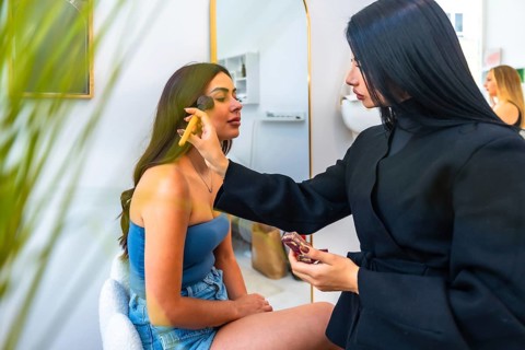 Professional makeup artist applying foundation on a client's face using a brush, enhancing her