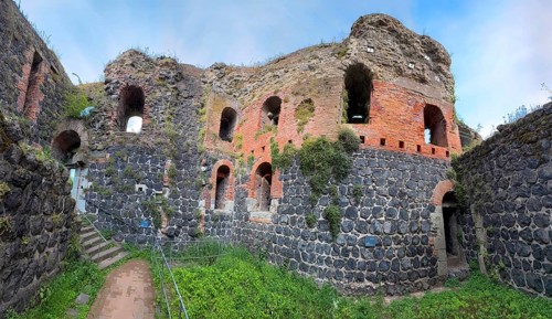 Panoramic photo of interior of northern inner part with partially restored secured masonry of ruins