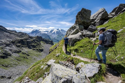 Mountaineer on hiking trail in mountain landscape, descent at Col du Louvie, view of the summit of