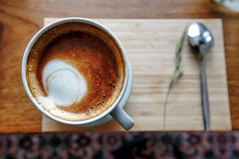 Cup of coffee with milk foam, cappuccino, coffee speciality on a wooden board, view from above,