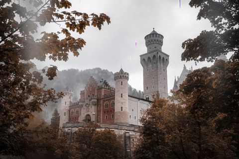 The romantic Neuschwanstein Castle framed by autumn leaves in the mist, Schwangau, Bavaria