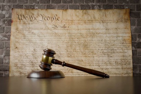 United states constitution on wall with gavel resting on table in front