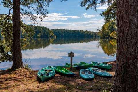 Plastic rental kayaks, canoes and paddleboards on the shore of Pin Oak Lake at The Lodge hotel in