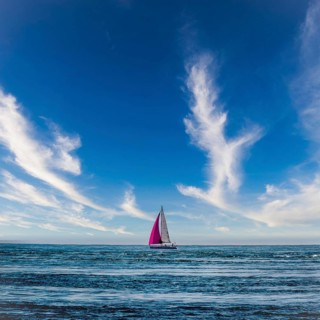 A sailboat glides across the Atlantic Ocean near Brittany, France. Its colorful sails contrast