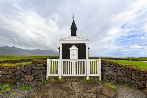 Traditional black church with white wooden door and stone wall, wooden church Budakirkja, Búðir,