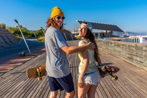 Smiling young adults skateboarding on a sunny boardwalk, capturing the essence of carefree summer
