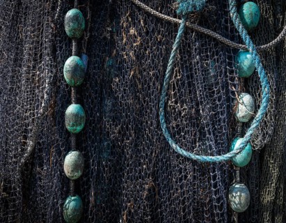 Detailed close-up of a fishing net with ropes and blue-green floats, harbour, Ringkøbing,