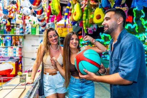 Happy friends enjoying time at an amusement park, playing a basketball game and celebrating their
