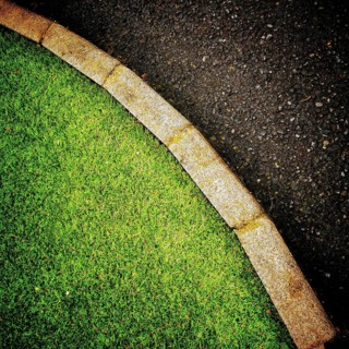 The vibrant green grass curves smoothly alongside a dark asphalt pathway, creating a pleasing