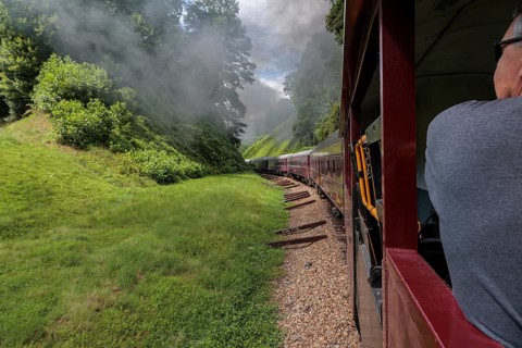 Steam from the Great Smoky Mountains Railroad hangs in the air as the train rounds a curve through