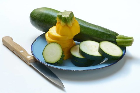 Green and yellow courgettes on a plate with a knife, Cucurbita pepo