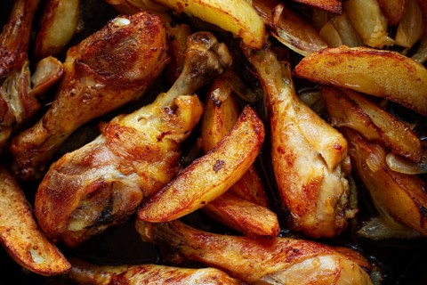 Fried chicken drumsticks with potato slices, in a clay pan, baked in the oven, with spices,