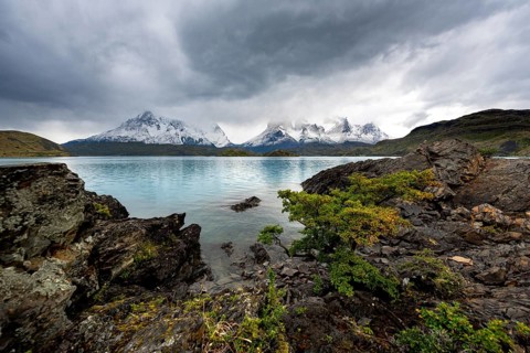 Cloudy mountain range Cuernos del Paine, shore of the blue lake Lago Pehoe in the evening light,