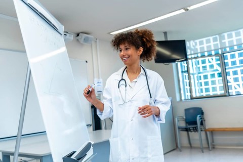 Female medical professional explaining a concept drawing on a whiteboard during a medical lecture