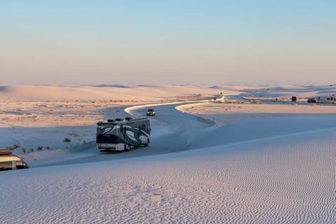 Vehicles being driven on cleared roads through the white gypsum dunes at White Sands National Park