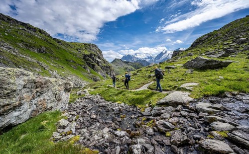 Mountaineers on a hiking trail along a mountain stream in a mountain landscape, descent at Col du