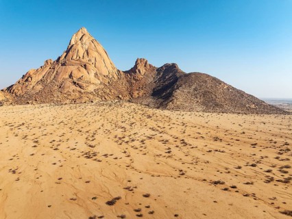 The isolated Spitzkoppe mountain (1728 m) majestically rises above the surrounding desert plains.