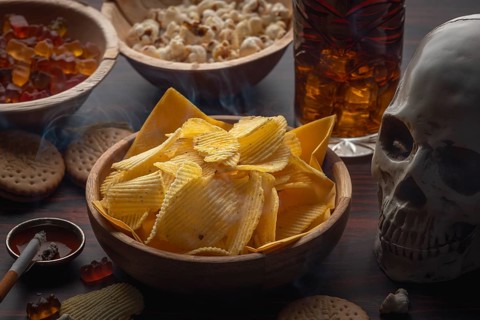Skull and crossbones next to crisps, jelly babies, popcorn, cola and a smoking cigarette