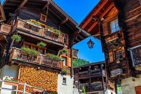 Old wooden houses in log construction, decorated with flowers, historic village centre, Grimentz,