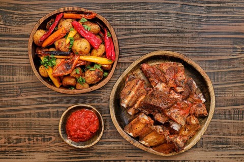 Succulent short beef ribs roasted in the oven served alongside a medley of grilled vegetables and a