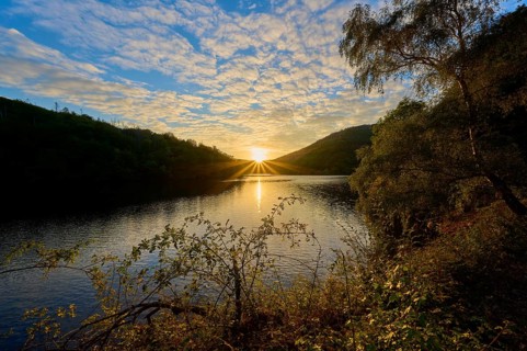 The sun sinks behind hills on the lake, golden glow and reflecting water surface, summer, Rursee,