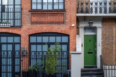 Historic brick building labelled Contractors, green door, Kensington, London, England, United