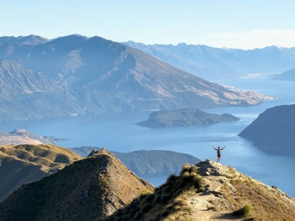 Person with outstretched arms on the hiking trail to Roys Peak Lookout, Lake Wanaka, Wanaka, South