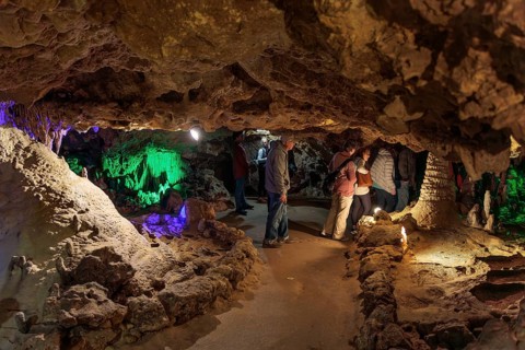 Tourists walking past limestone rock formations in a cave at Florida Caverns State Park in the