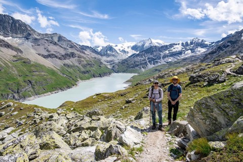 Mountaineer on a hiking trail at a blue mountain lake, reservoir Lac des Dix, behind mountain peak