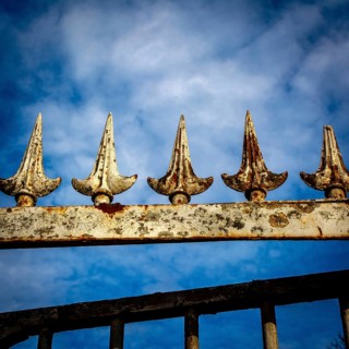 Close-up view of an ornamental iron fence featuring pointed spikes, showcasing rust and weathering
