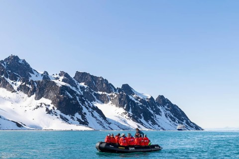 Zodiac in front of mountain range with snow, sea, Fugelfjorden, Spitsbergen, Svalbard