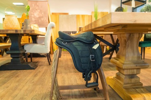 A saddle lies on a wooden chair in a furniture shop, surrounded by rustic woodwork, Sindelfingen,