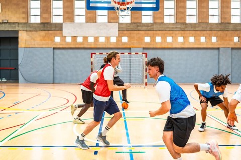 Basketball players running and practicing in a gymnasium, showcasing teamwork and skill during an