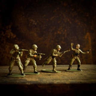 Four toy soldiers stand in various combat stances, ready for action on a weathered wooden surface.