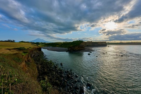 Coastal landscape with sea, cliffs and cloudy sky, calming atmosphere, Opunake, Egmont Volcano,