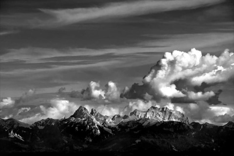 Clouds drift over the striking peaks of the Swiss mountains, showcasing a breathtaking view near