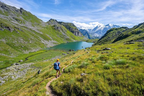 Mountaineer on hiking trail in picturesque mountain landscape, view of mountain lake Lac du Louvie