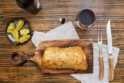 Delicious homemade roasted pork meat and pickled peppers on a rustic wooden table surrounded with