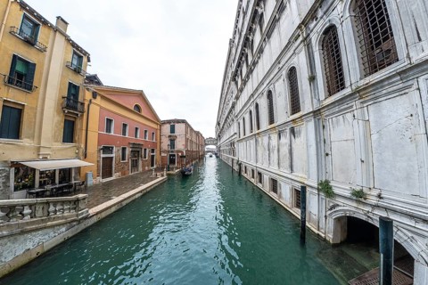 Serene canal in venice with traditional gondola navigating towards distant bridge, showcasing