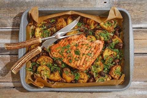 Juicy roasted turkey breast is beautifully presented on a tray with golden, seasoned potatoes and