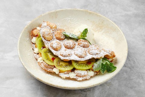 A delightful dessert showcases a fluffy shell filled with fresh kiwi slices and whipped cream,