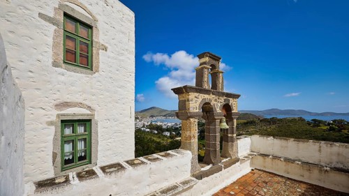Bell tower on the roof of a white building overlooking the sea, Monastery of the Revelation, Moni