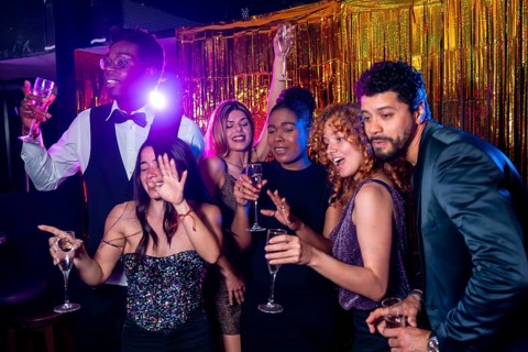 Group of cheerful elegant friends having fun together and drinking sparkling wine while dancing and