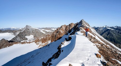 Mountaineer on rocky ridge with snow, mountain peaks Wilder Freiger and Wilder Pfaff in the