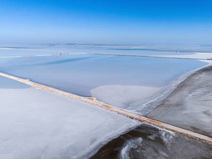 A vast salt lake under a clear blue sky, with simple geometric lines and footbridge, aerial view,