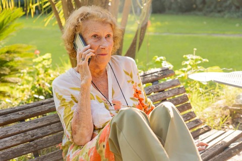 Senior woman enjoying a conversation on her mobile phone while sitting on a wooden bench in a