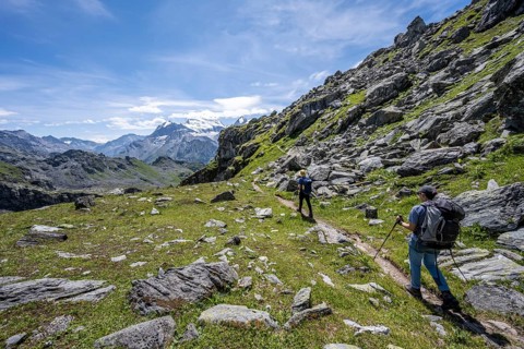 Mountaineer on hiking trail in mountain landscape, descent at Col du Louvie, view of the summit of