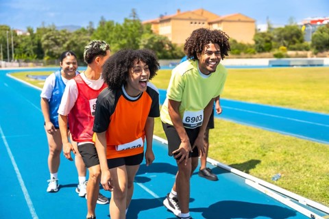 Group of athletes catching their breath and recovering after completing a race on a vibrant blue