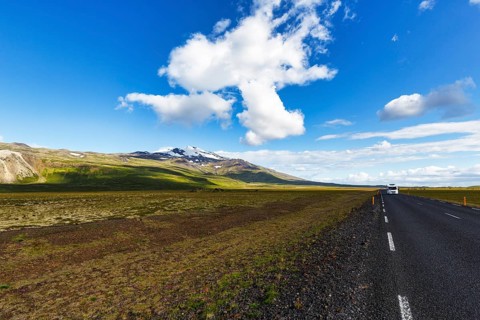 Tarmac road through barren volcanic landscape with a view of the snow-covered Snæfellsjökull