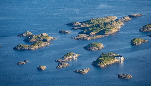 Small rocky islands with individual houses in the sea, archipelago islands, near Henningsvær,